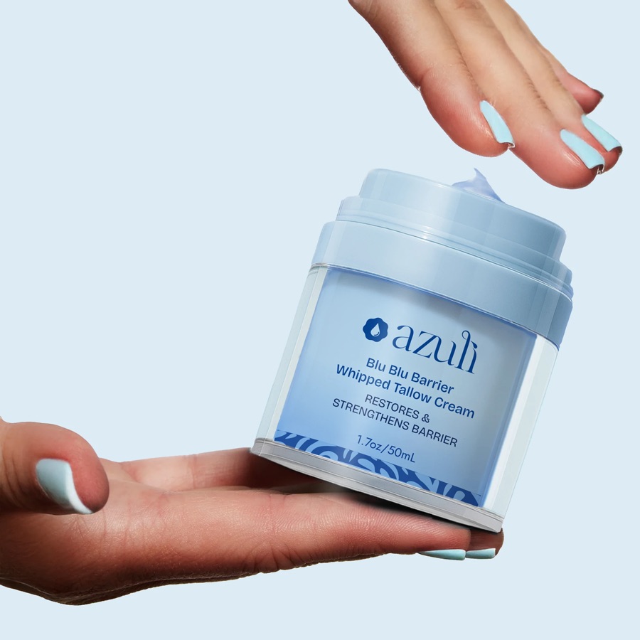 A Blu Blu Barrier jar resting on an open palm, another hand reaching for the pump